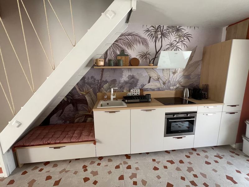 Cuisine sous l'escalier, papier peint palmiers et banquette